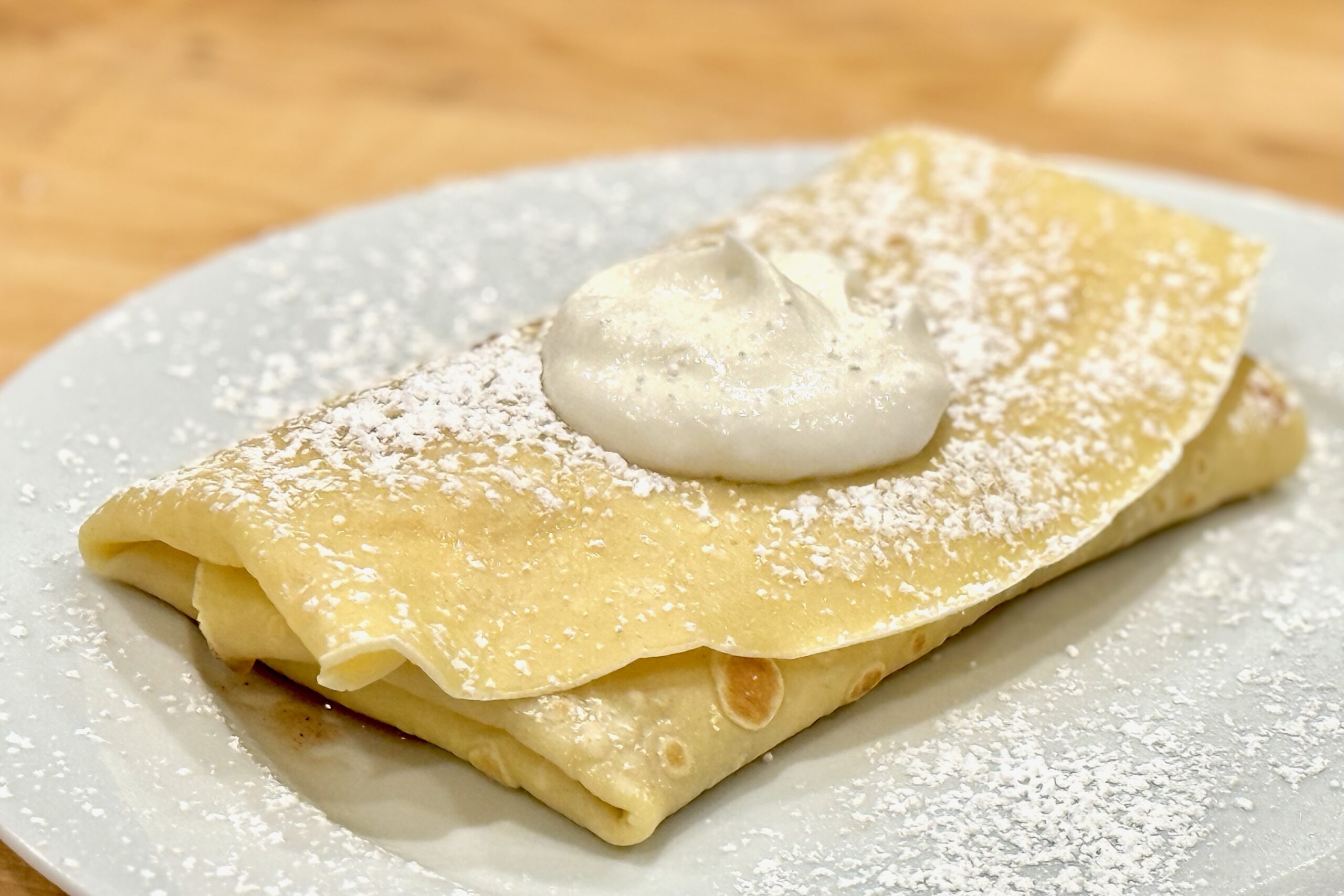 Apple-filled crêpe with whipped cream and a dusting of powdered sugar